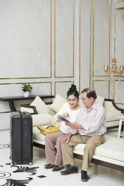 Casal Sênior Sentado Sala Hotel Lendo Dados Computador Tablet — Fotografia de Stock