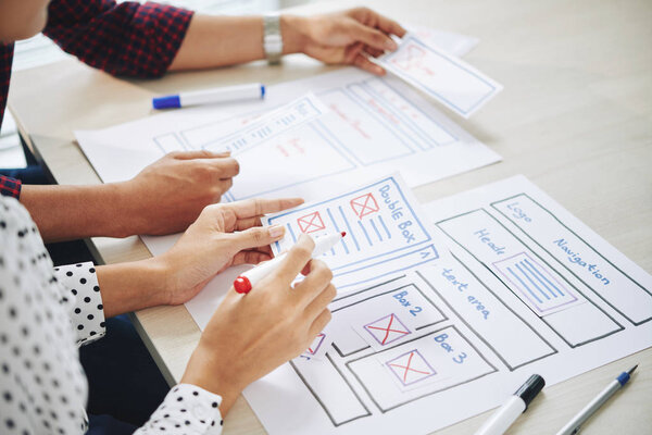 Команда дизайнеров пользовательского интерфейса обсуждает идеи для интерфейса веб-сайта на встрече
