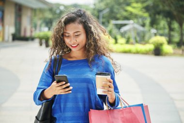 Fincan taze sıcak içecek ve kağıt torbalar sokakta güzel Endonezya hanımla 