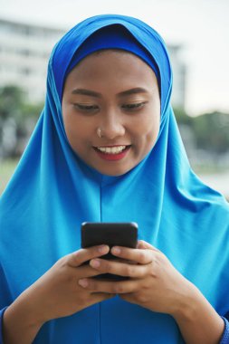 Gülümseyen ve modern smartphone tarama çekici Endonezya kadın 