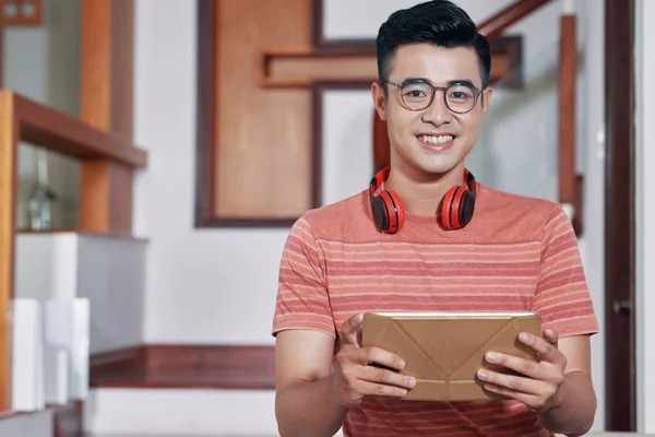 Portrait of happy young Vietnamese man with digital tablet and headphones