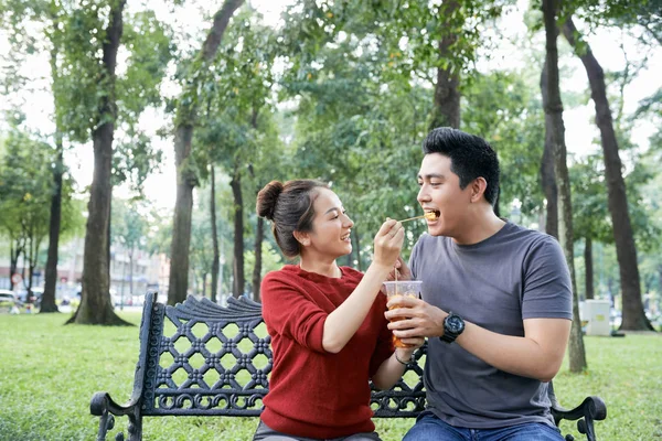 愉快的年轻亚洲妇女喂她的男朋友与街头食品在公园 — 图库照片