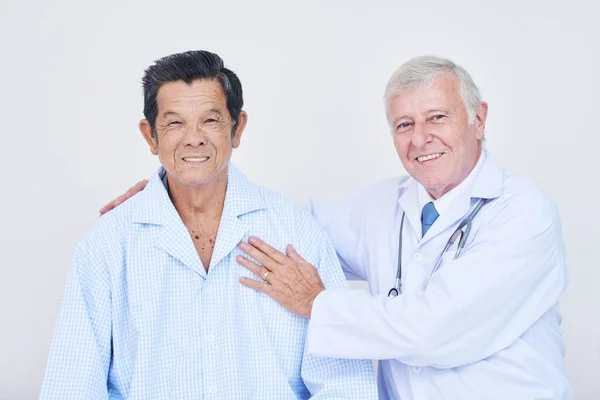 高齢医師笑顔と区のハグのアジアの患者ながらカメラ目線 — ストック写真