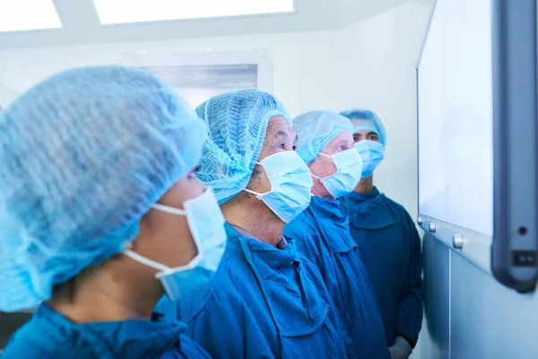 Vue Latérale Quatre Chirurgiens Masqués Debout Dans Bloc Opératoire Moderne — Photo