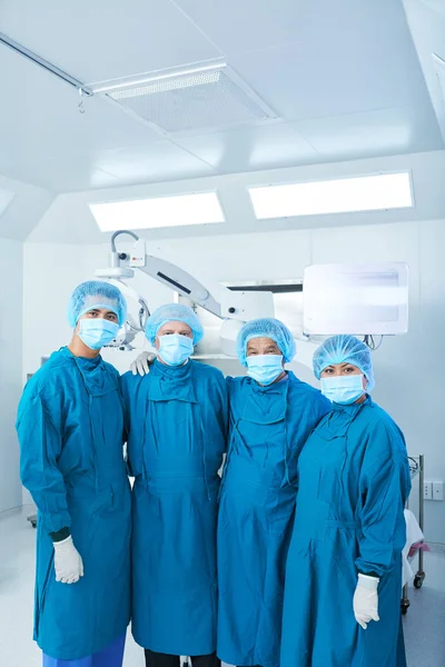 Four Doctors Surgeons Uniform Hugging Each Other Looking Camera While — Stock Photo, Image