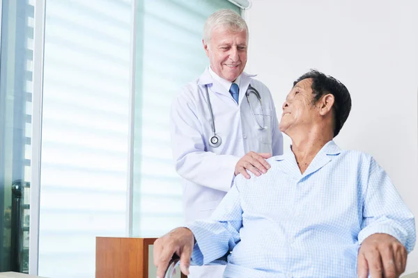老人医師制服笑顔と近代的なクリニックの病棟に立っている間年配のアジア男性をサポート — ストック写真