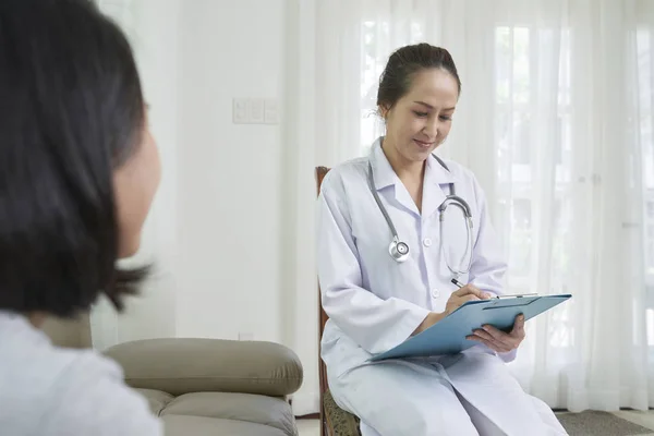 Usmívající Praktický Lékař Zapisování Poznámek Při Poslechu Pacientka — Stock fotografie