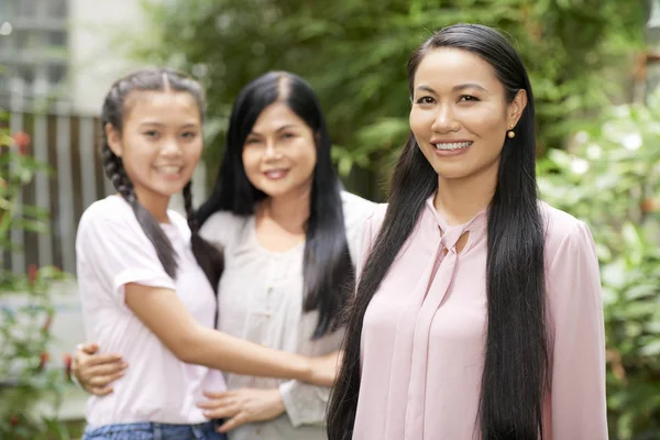成人亚洲妇女与成熟的妇女和十几岁的女孩背景微笑在照相机 — 图库照片