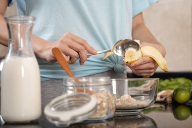 Ev kadını olgun muz müsli bir kase içine ekleme