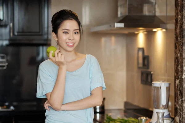 美しいこぼれるような笑みを浮かべて食べる青リンゴと幸せな若いアジア女性 — ストック写真