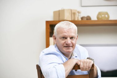 Office sandalyede oturan ve kameraya bakarak orta yaşlı işadamı portresi