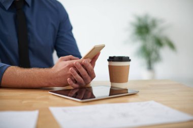 Office masada oturan ve onun telefonundaki mesajları kontrol iş yürütme yakın çekim görüntüsü