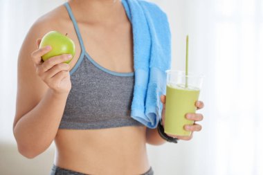 Taze yeşil elma ve detoks güler yüzlü beyaz arka plan üzerinde tutan spor içinde tanınmayan kadın kırpma vurdu