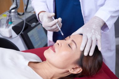Olgun Asyalı kadın Botox enjeksiyon güzellik salonunda Başlarken