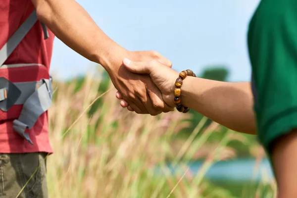 Hand of hiker reaching for help of his friend when climbing