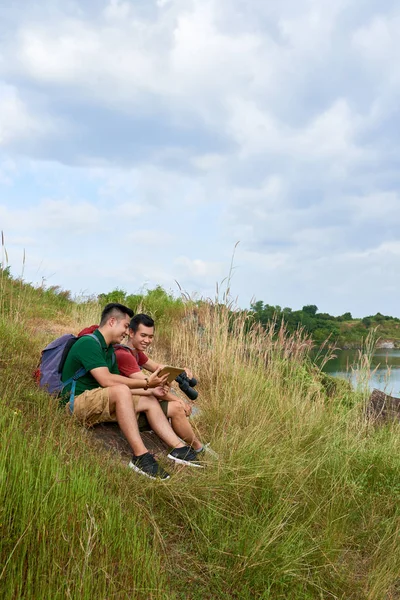 Vrolijke Wandelaars Met Digitale Tablet Zittend Heuvel Aan Het Meer — Stockfoto