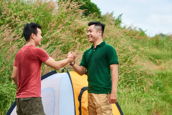 快乐的朋友在野营地搭起帐篷后握手 — 图库照片