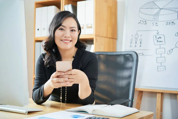 Muito Sorridente Chefe Departamento Feminino Com Smartphone Sentado Mesa Escritório — Fotografia de Stock