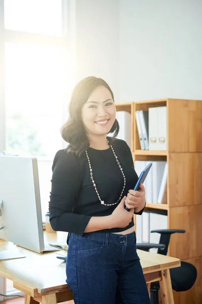 タブレット コンピューター立って彼女のテーブルの横に 幸せな若い女性室長 — ストック写真