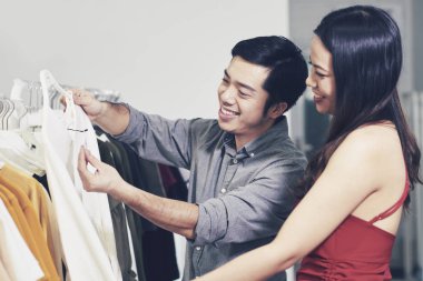 Neşeli genç erkek ve kız arkadaşı satın alma mağaza giyim gülümseyen