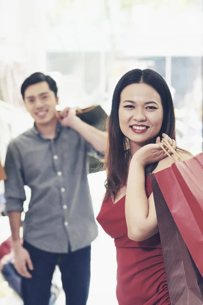迷人的年轻女子和她的男朋友拿着纸袋 对着镜头微笑 — 图库照片