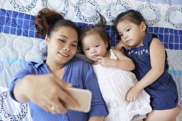 Młoda Kobieta Wietnamski Małe Córki Leżąc Kanapie Pozowanie Selfie — Zdjęcie stockowe