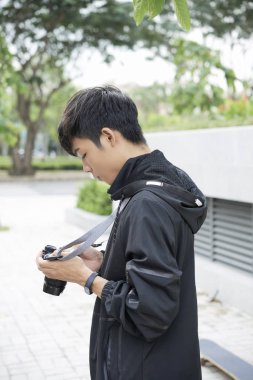 Genç Asyalı fotoğraf fotoğraflar onun fotoğraf makinesi üzerinde denetimini