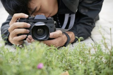 Profesyonel fotoğrafçı çiçekler ve çim fotoğraflarını çekerken yatan