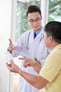 Tıp üst düzey hastası ile tartışan genç Vietnamlı doktor gülümseyen