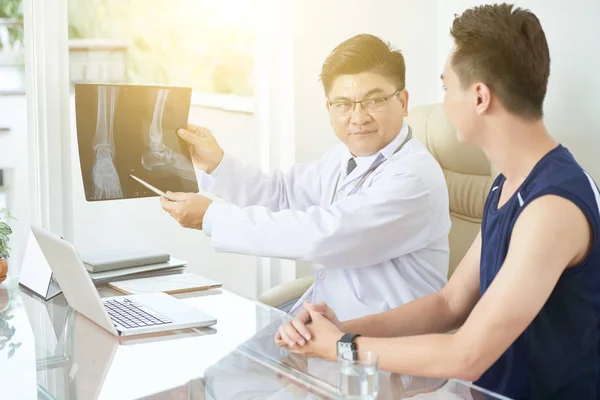 Доктор Показывает Пациенту Рентген Сломанных Ног — стоковое фото