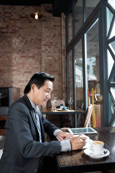 Mature Asian Businessman Sitting Window Coffee Shop Writing Ideas Thoughts — Stock Photo, Image