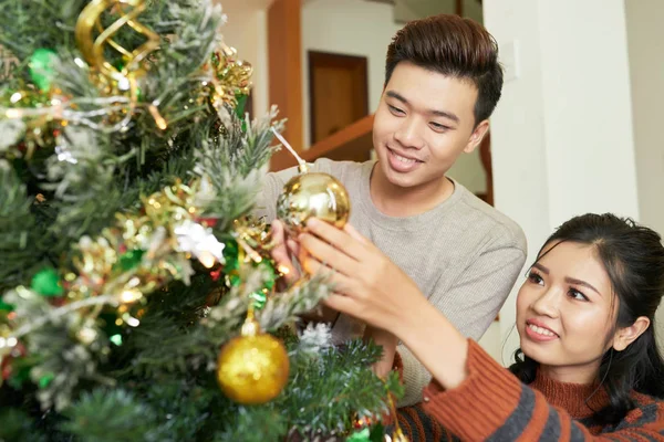 Neşeli Genç Evli Çift Koyarak Tinsel Baubles Noel Ağacı Üzerinde — Stok fotoğraf