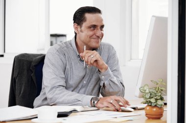 Coworking ofiste çalışan yakışıklı adam gülümsüyor. Bilgisayar başında oturan