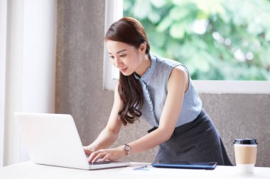 Meşgul Sekreter yakınındaki office masada duran dizüstü bilgisayarda yazarak