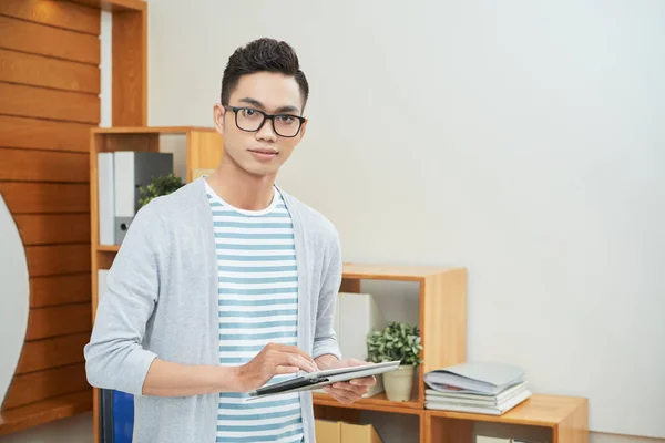 现代年轻的亚洲男人穿着休闲服装 戴着眼镜站在桌子上看着相机 — 图库照片