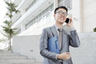 Açık havada yürürken telefonda konuşurken neşeli yakışıklı işadamı
