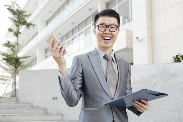 Porträtt Skrattar Upphetsad Ung Affärsman Med Smartphone Och Dokumentet Stående — Stockfoto