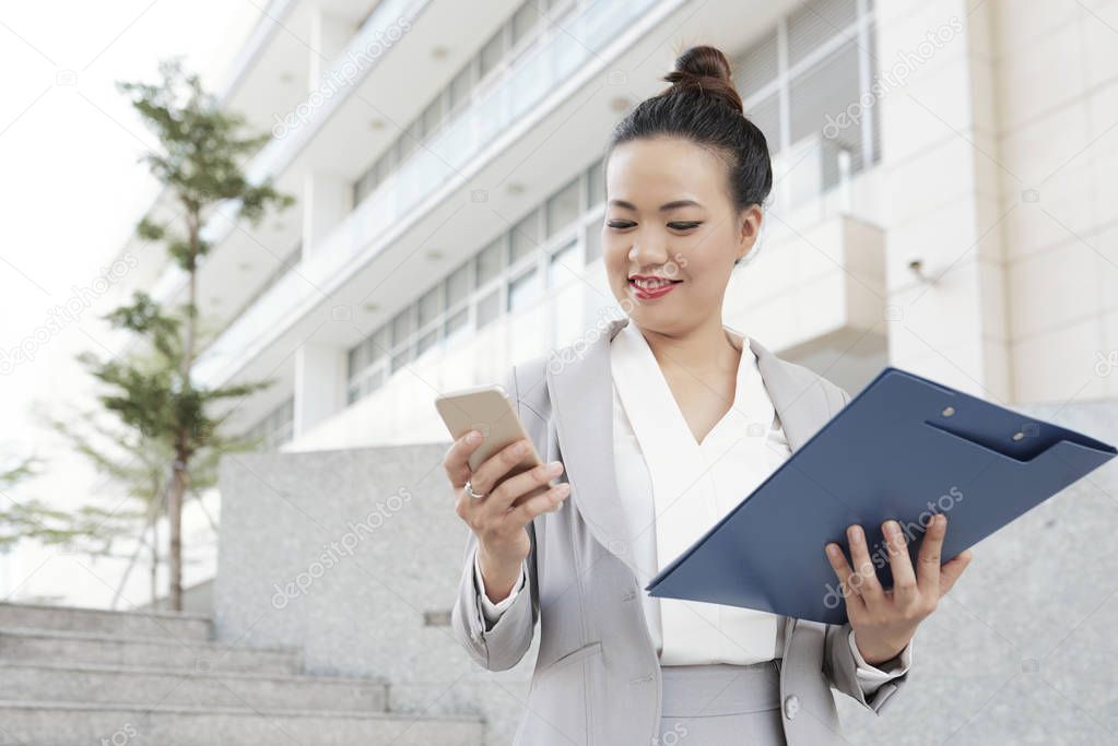 Successful Asian business woman with document and smartphone