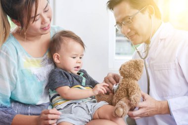 Biraz sabırlı sakinleştirmeye oyuncak ayı, kalp atışına dinleme çocuk doktoru gülümseyen