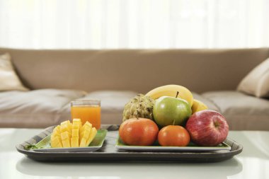 Dilimlenmiş ananas ve odasındaki masada tepsisindeki taze meyve suyu ile taze meyve Close-Up