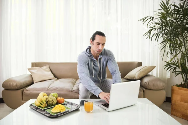 Young Man Sitting Couch Typing Laptop Table Tray Fresh Fruits — Stock Photo, Image