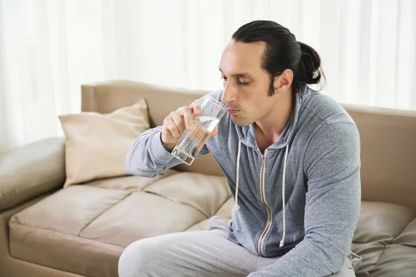 Joven Saludable Bebiendo Agua Mientras Relaja Sofá Casa —  Fotos de Stock