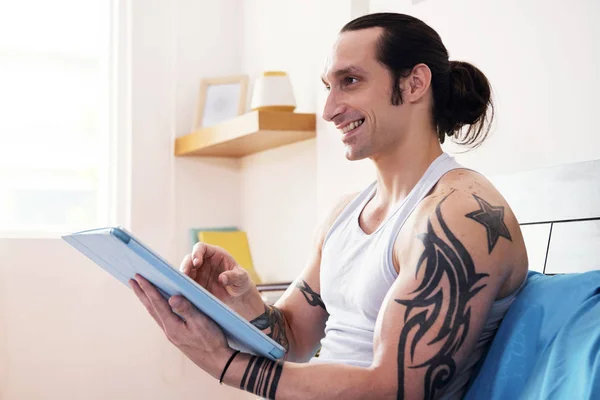 Молодой Мускулистый Мужчина Татуировками Руках Используя Планшетный Компьютер Улыбаясь Сидя — стоковое фото