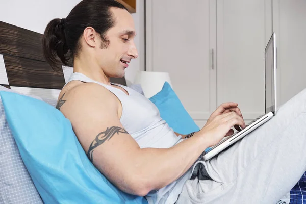 Smiling Man Sitting Comfortably His Bed Leaning Pillow Working Online — Stock Photo, Image
