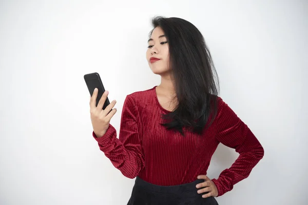 优雅的亚洲女孩的肖像站在和看智能手机在她的手在白色背景 — 图库照片