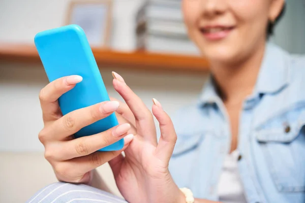 Close-up of female blogger using her smartphone for work, she communicating with followers online