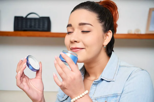 Jovem Mulher Segurando Creme Facial Suas Mãos Apreciando Cheiro — Fotografia de Stock