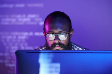 Bilgisayar ekranında kodlanmış verilerle çalışma üzerinde konsantre gözlük genç ciddi programcı