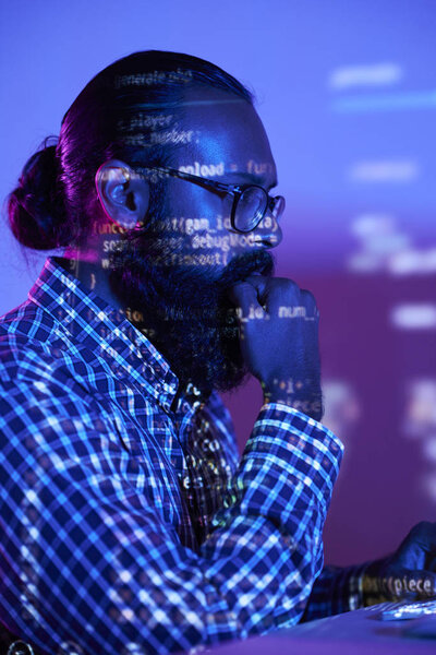 Double exposure shot of serious bearded programmer and reflection of coded data on monitor