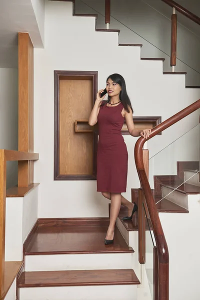 穿着红色衣服的亚洲美女走在楼梯上 用手机说话 — 图库照片
